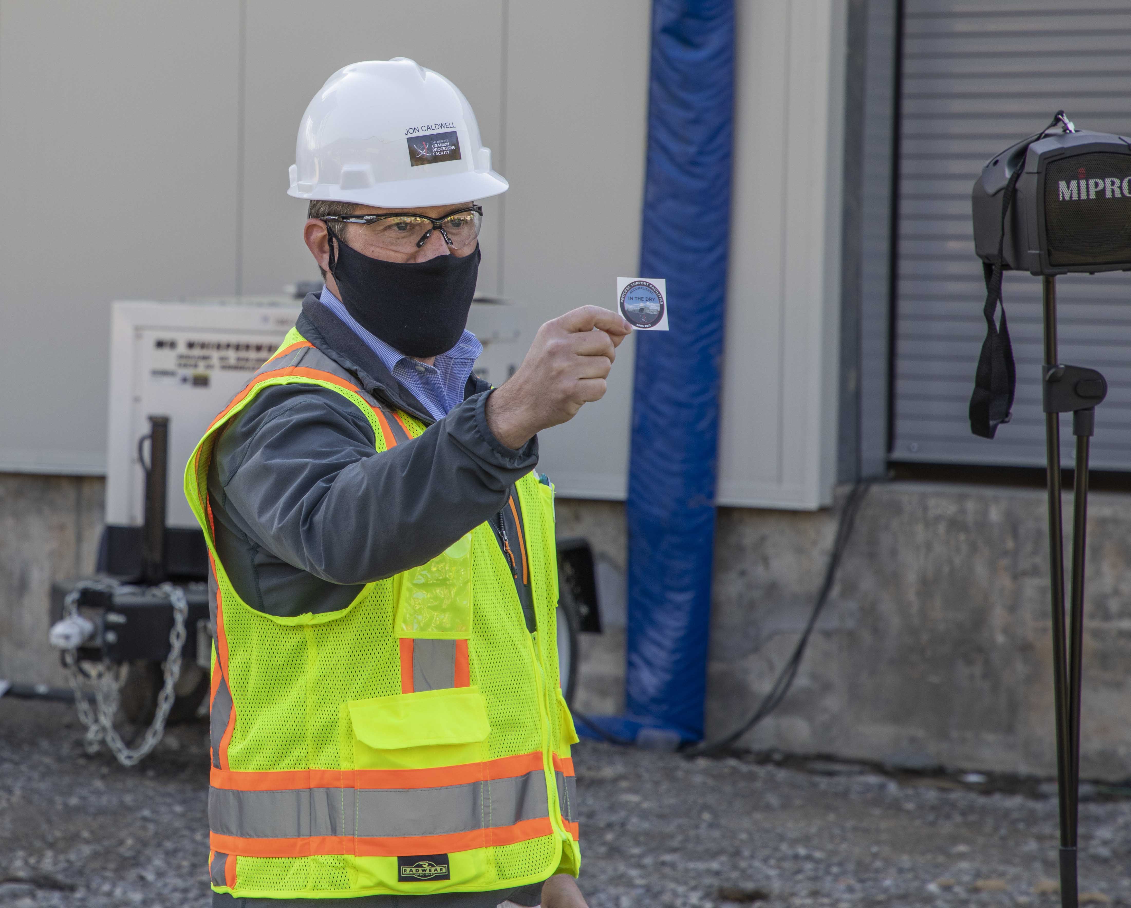 PSF Federal Project Director holding a UPF hard hat sticker to commemorate the milestone