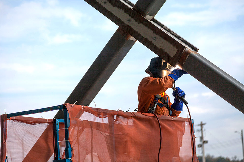 A welder works on the cross bracing for the Mechanical Electrical Building (MEB) structure. MEB was the first of UPF’s three main facilities to go vertical. 
