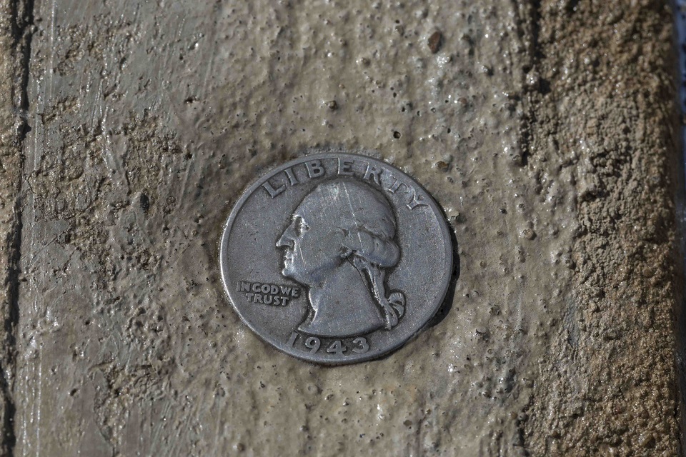 Holding to the masons’ tradition, a 1943 coin, the year Building 9731 was built, was placed into the pavement.
