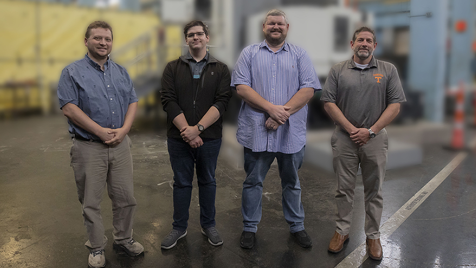 The Tooling Project Team pictured standing in front of a machine on the shop floor.  