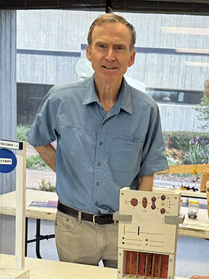 Ken L. poses with one of several handcrafted models of the nuclear fission process shown to students