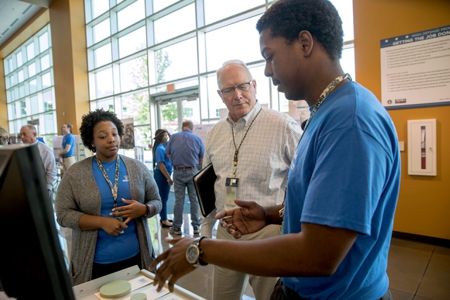 Tom Hayden (center) listens to Y-12 interns share results from their projects.