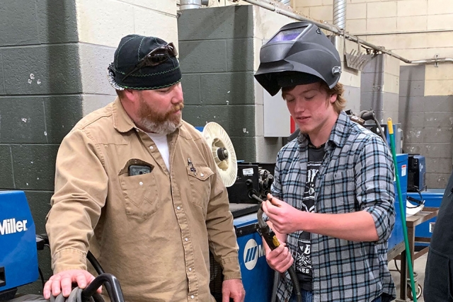 Y-12 National Security Complex welder Travis Scott (left) and Anderson County Career and Technical Center student Aaron discuss how to replace welding torch components and troubleshoot issues that could lead to poor welding performance.