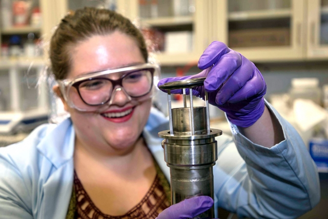 Y-12 intern Colleen Hyer inspects the sublimation chamber she and intern Dalton Parker designed.