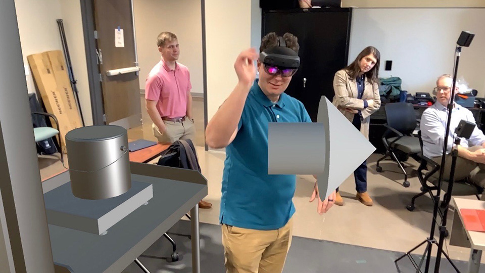An operator is showing virtual additive manufacturing capability in a collaborative XR environment. 