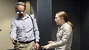 Toby Williams, Director of Global Security Analysis and Training (GSAT), tests out an AR headset under the instruction of Avrio Analytics CEO Alicia Caputo.