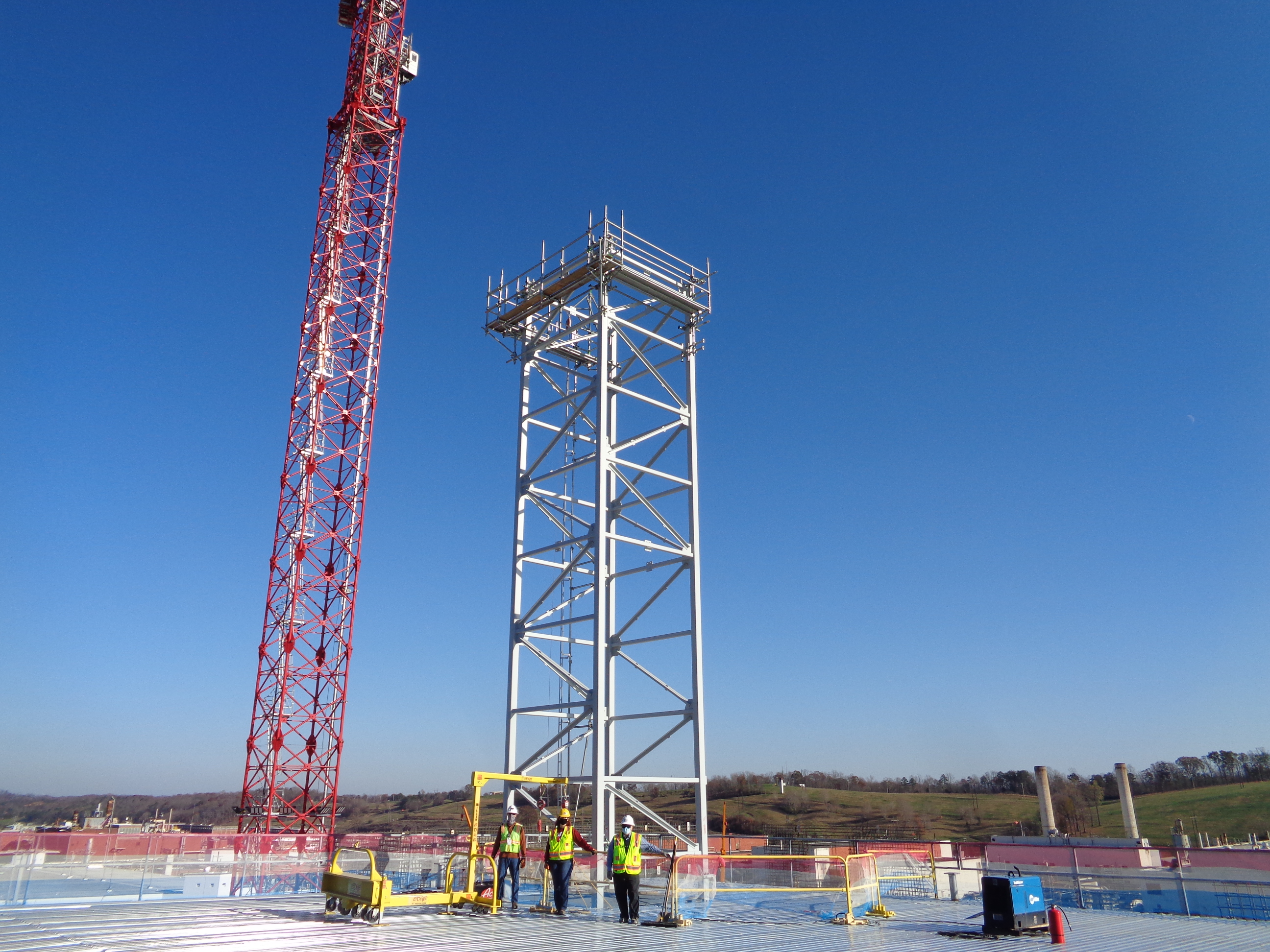 UPF employees stand on the roof of the Salvage and Accountability Building in front of the process off gas stack.