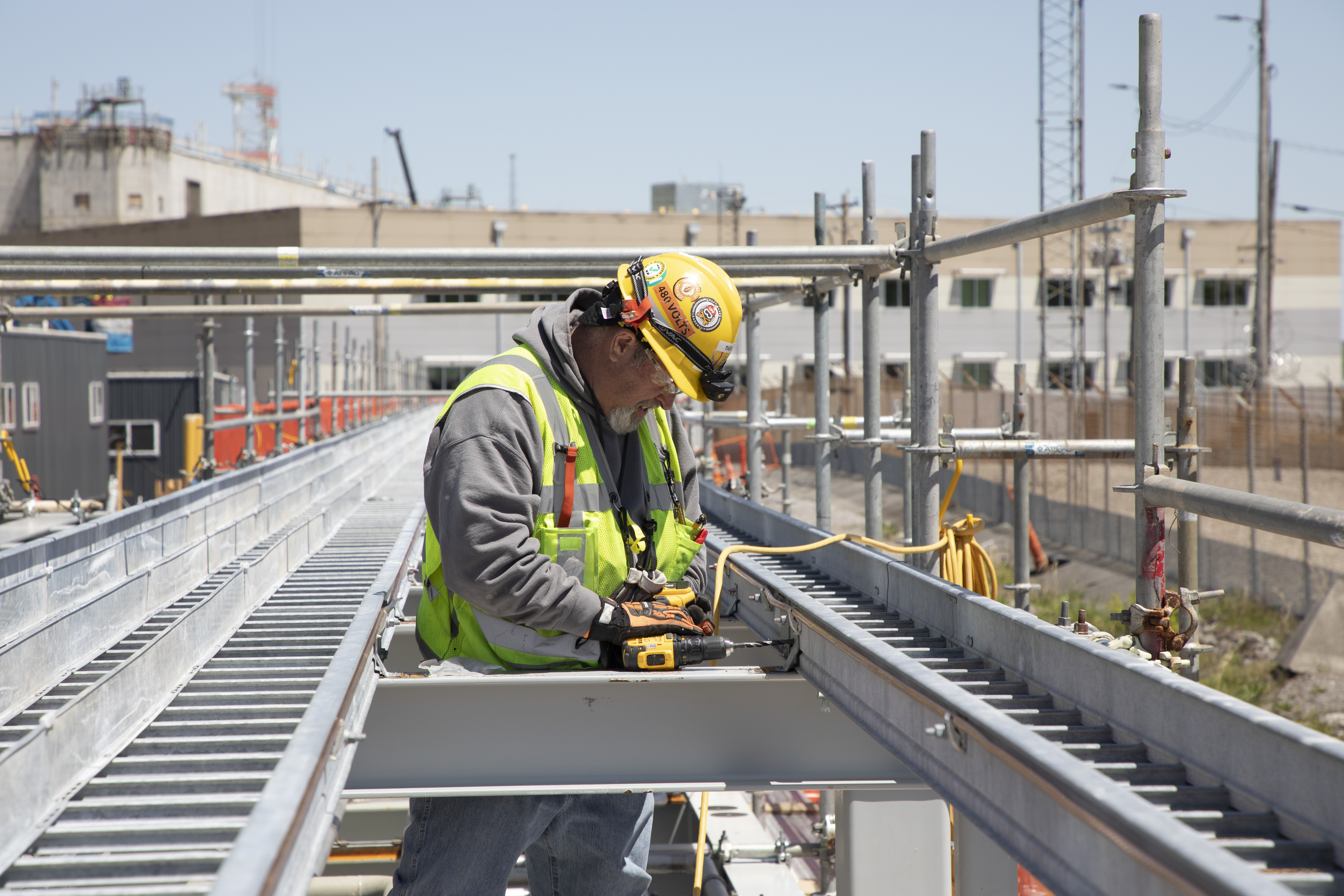 Electrician installing cable tray on pipe rack 