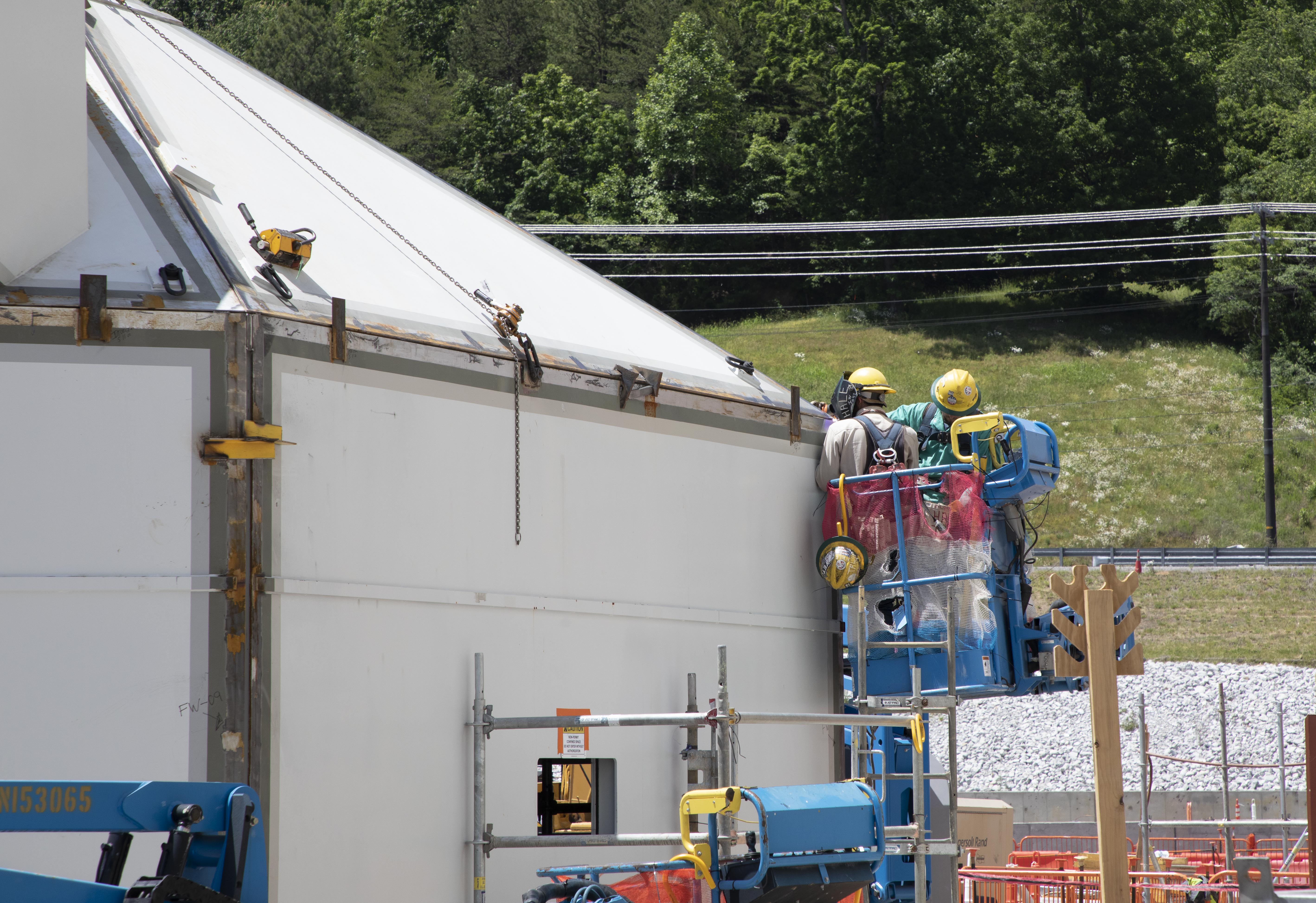 Ironworkers welding a Main Process Building security personnel enclosure 