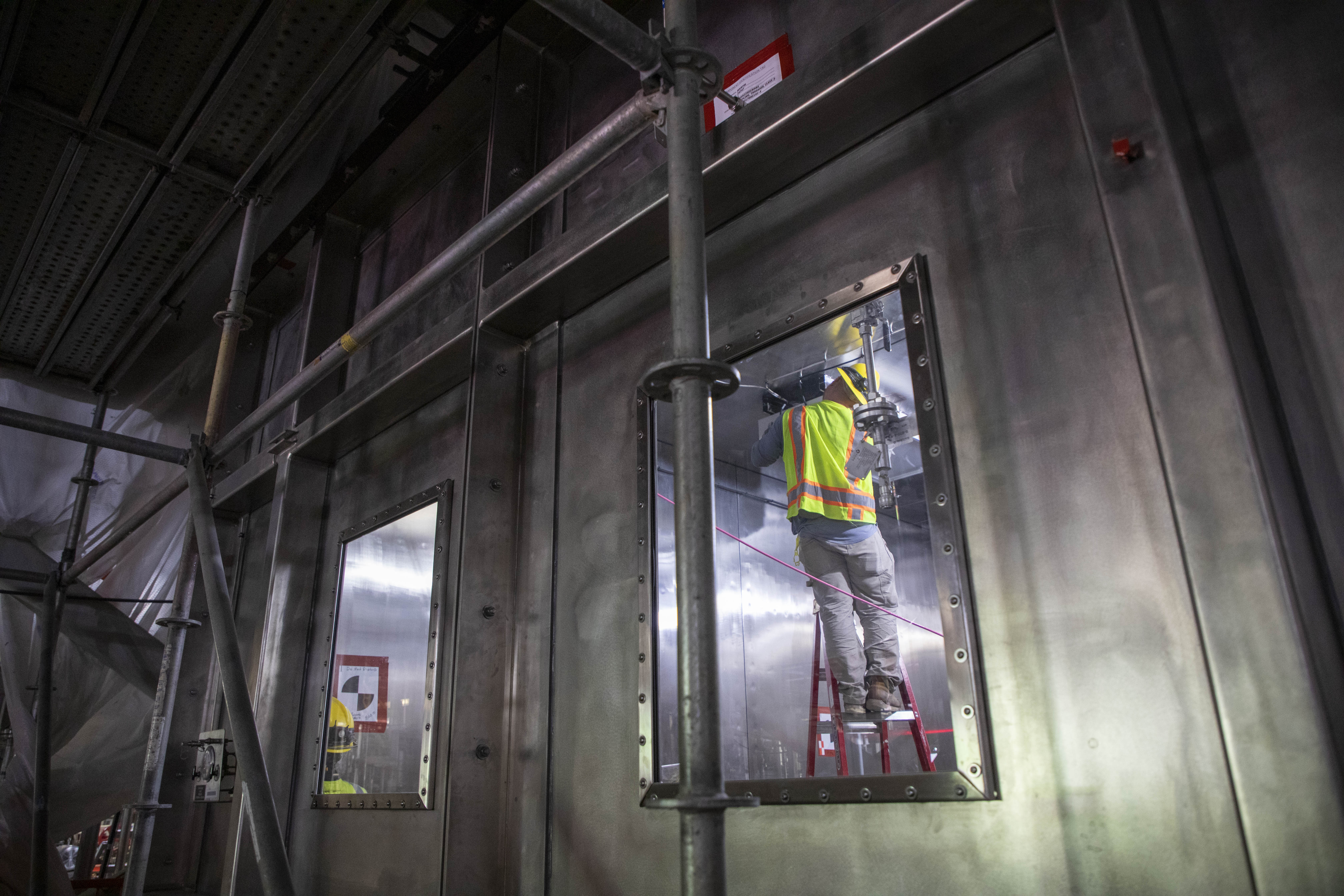 An electrician working on the Salvage and Accountability Building Waste Preparation Walk-in Enclosure 