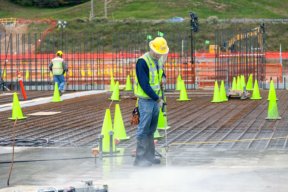 A worker cleans recently cured concrete on the foundation of UPF’s Main Process Building, a 252,000-square-foot building which will house casting, special oxide, and some chemical recovery processes.   