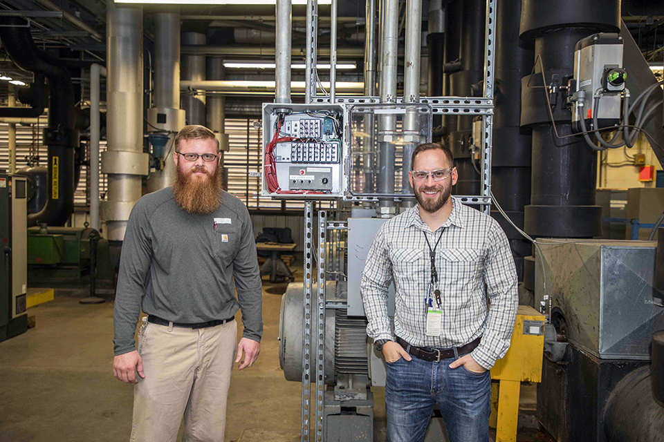 Ronald Bolden Jr. (left) and Luke Birt, pause for a photo with Building 9767-13’s installation