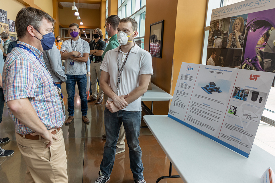 Adry Lain (center), an intern who worked with Y 12 Development, explains his project at the 2022 Intern Expo.