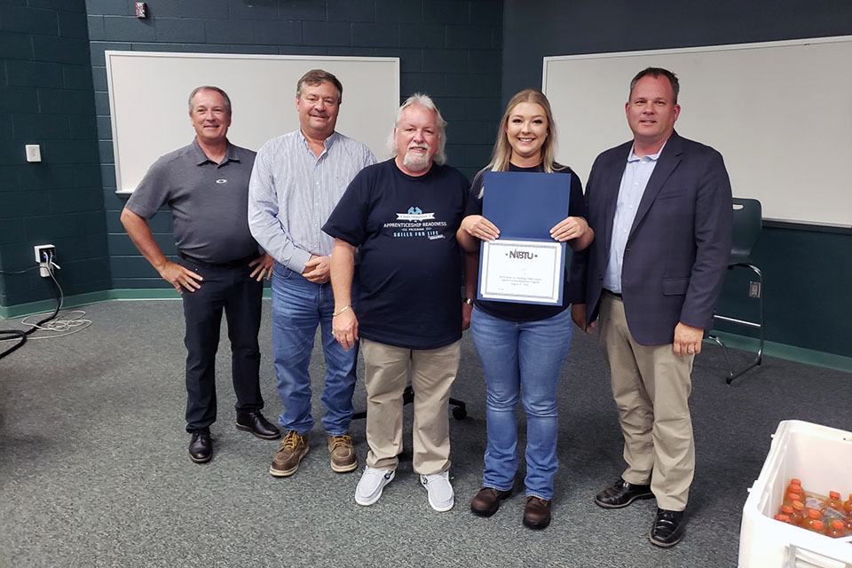 Y-12 Sheet Metal Apprentice Erin Scott (second from right) holds a certificate at the ETARP graduation ceremony. With her from left to right are: UCOR Labor Relations Manager Len Morgan, General Superintendent John Arbaugh, East Tennessee Apprenticeship Readiness Coordinator Chris Branham, and CNS Project Director John Platt II.