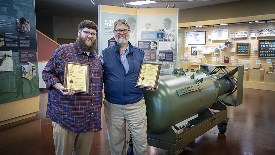 Will (left) and Ed R..(right) showcase the plaques they received for their joint patent, “Method of Making an Annular Radioisotope Target Having a Helical Coil-Shaped Foil Ribbon Between Cladding Tubes.”  