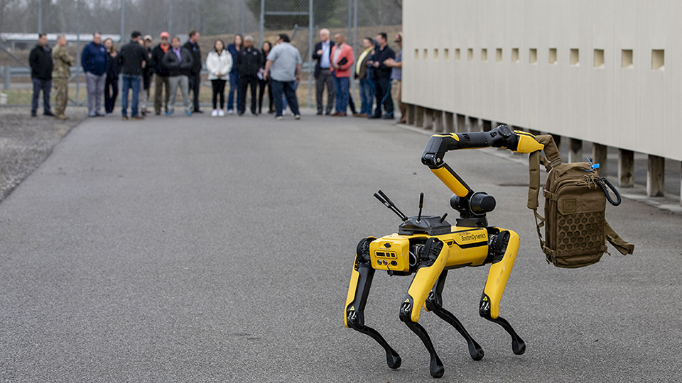 Mr. T demonstrating retrieval of a suspicious package while personnel monitor from a safe distance.  