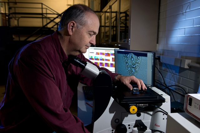 Bob Bridges examines a cross sectional view of a titanium alloy electron beam weld with an optical inverted microscope with polarized light illumination. The weld cross section can be seen on the monitor behind the metallograph.