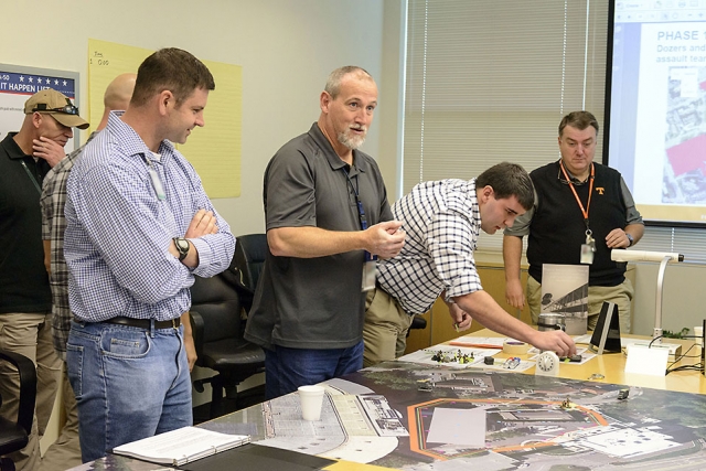 Mike Shattan (left), captain of the adversary team (or red team) and Army major, reviews his team’s next move on the battle board.