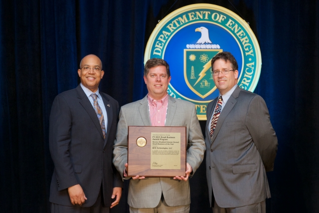 John Hale III and Drake Russell (at left and right), director and deputy director of the U.S. DOE Office of Small and Disadvantaged Business Utilization, congratulate Erik Connard, CEO and owner of BES Technologies, LLC, on his company’s receipt of DOE’s Service-Disabled Veteran-Owned Small Business of the Year award.