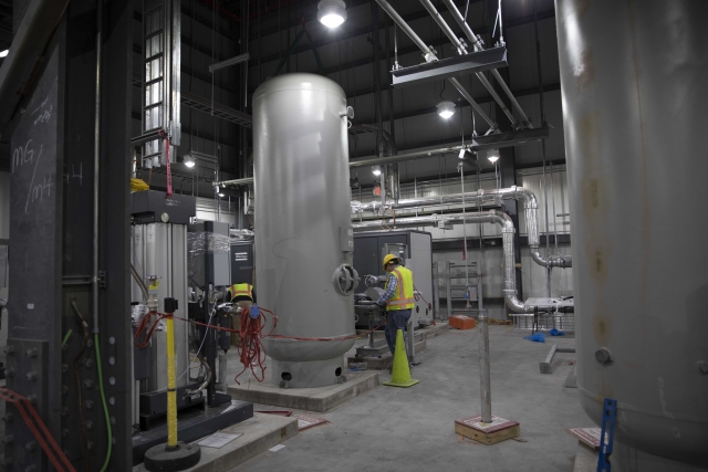 A UPF electrician inspects the wet receiver tank in the Mechanical Electrical Building, which will play a major role in providing safe air to the entire facility.