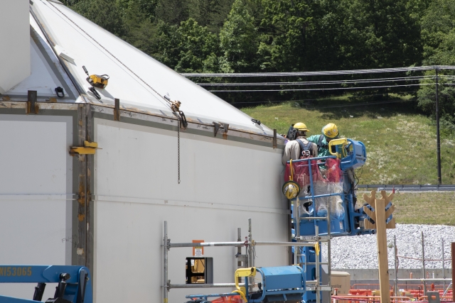 Ironworkers welding a Main Process Building security personnel enclosure 