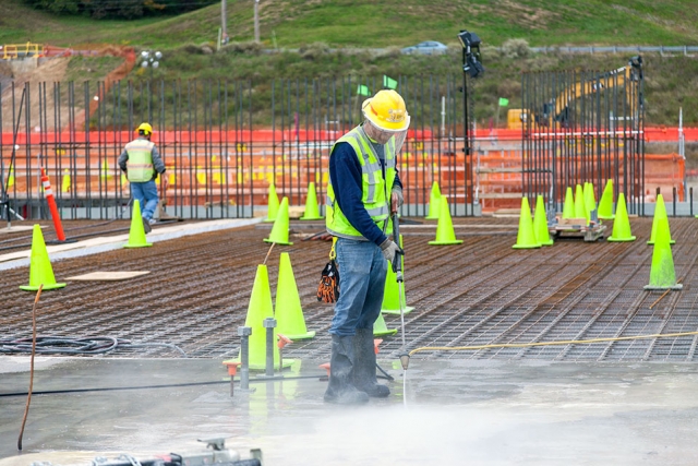 A worker cleans recently cured concrete on the foundation of UPF’s Main Process Building, a 252,000-square-foot building which will house casting, special oxide, and some chemical recovery processes.   