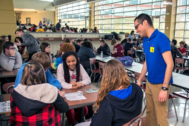 Jonathan Gomez of Y-12 interacts with students as they create aluminum foil boats to test the effects of liquid composition on buoyancy. 